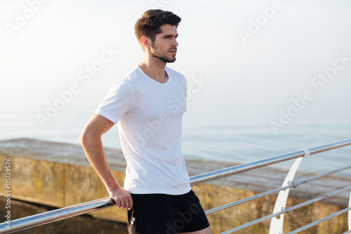 Serious young sportsman standing on pier