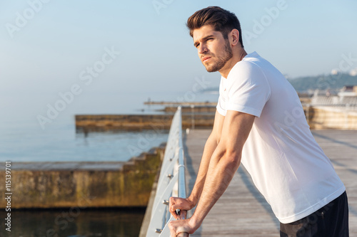 Thoughtful man athlete standing in pier in the morning