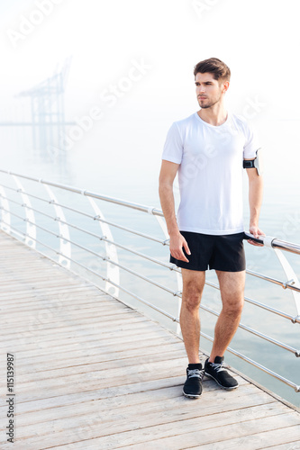 Sportsman standing on pier near the sea