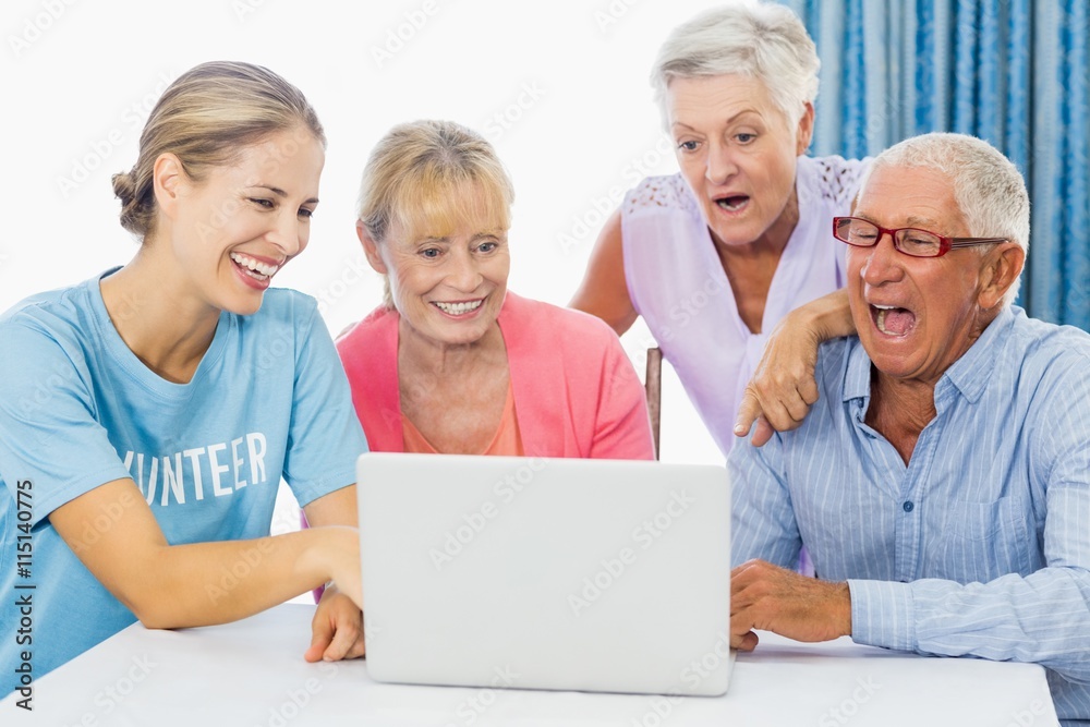 Volunteer and seniors using a laptop Volunteer and seniors using a laptop