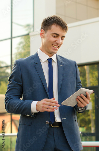 young man professional banker working on touch pad while standing in modern office space interior,purposeful male entrepreneur dressed in luxury clothes use digital tablet