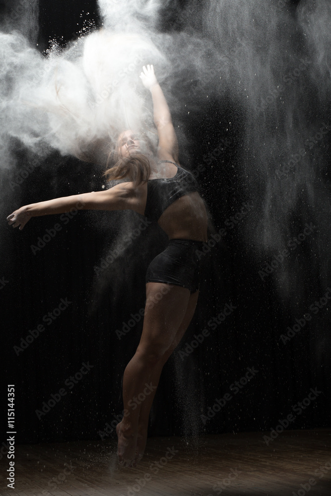 Ballerina dancing with flour on black background