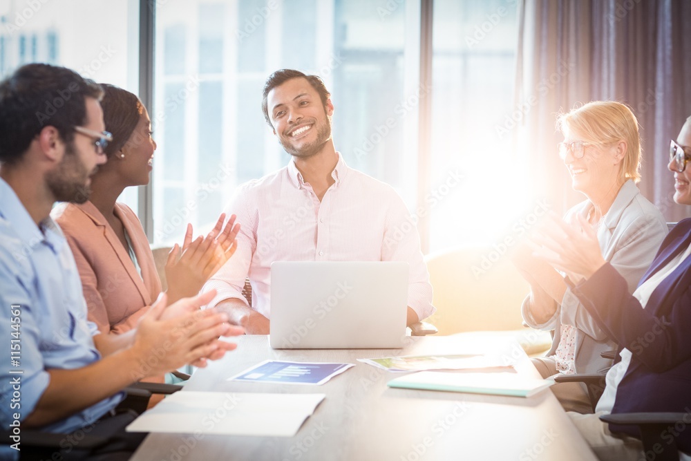Coworkers applauding a colleague after presentation Coworkers applauding a colleague after presentation