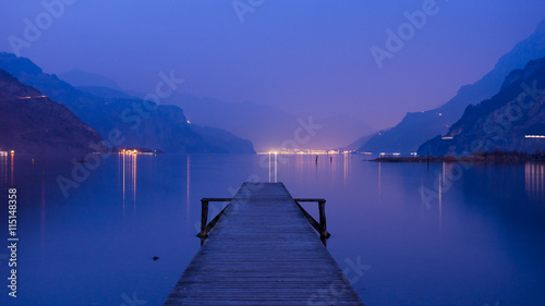 Panorama of mountain lake at sunset. Mountain range in the background. Wooden pier.