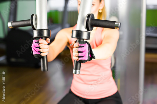fitness, sport, power-lifting and people concept - sporty girl building some muscles on a simulator