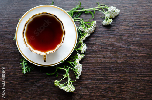 herbal yarrow tea in a porcelain cup on a dark wooden background