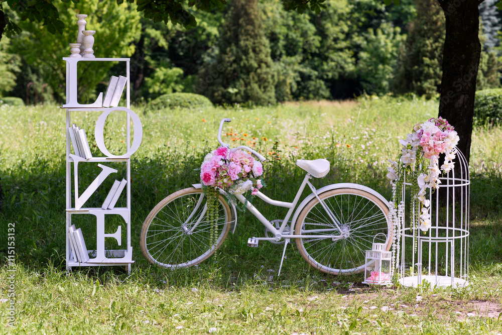 Fototapeta premium Wedding composition with love stand, a white bycicle and flowers