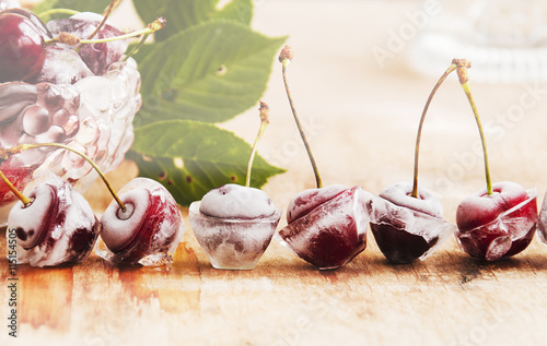 ripe cherries,ice cubes on wooden table, selective focus