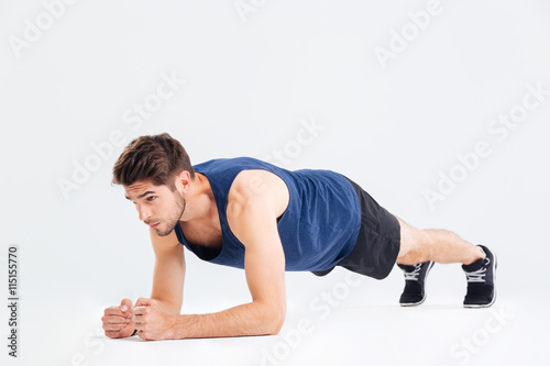 Focused handsome young sportsman doing plank core exercise