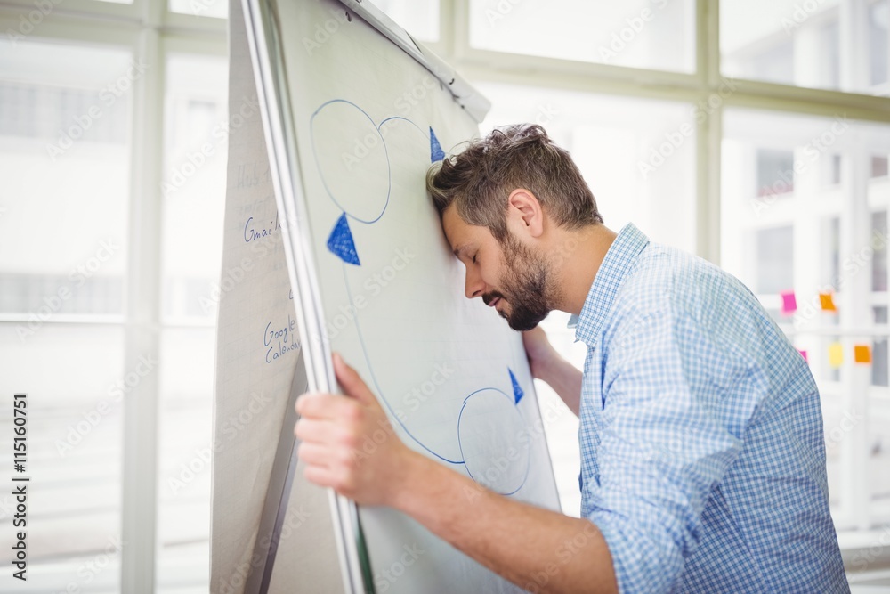 Fototapeta premium Tired businessman holding whiteboard in office