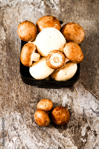 Fresh whole white mushrooms, or agaricus, in a bowl on a rustic
