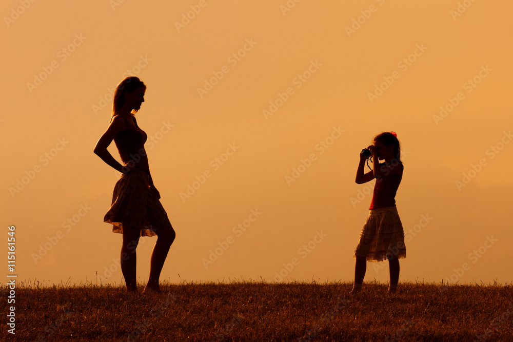 Silhouette of a daughter photographing mother