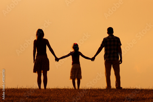 Parents enjoy watching sunset with their daughter.