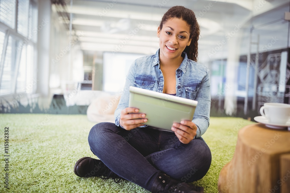 Obraz premium Businesswoman using tablet while sitting on carpet 