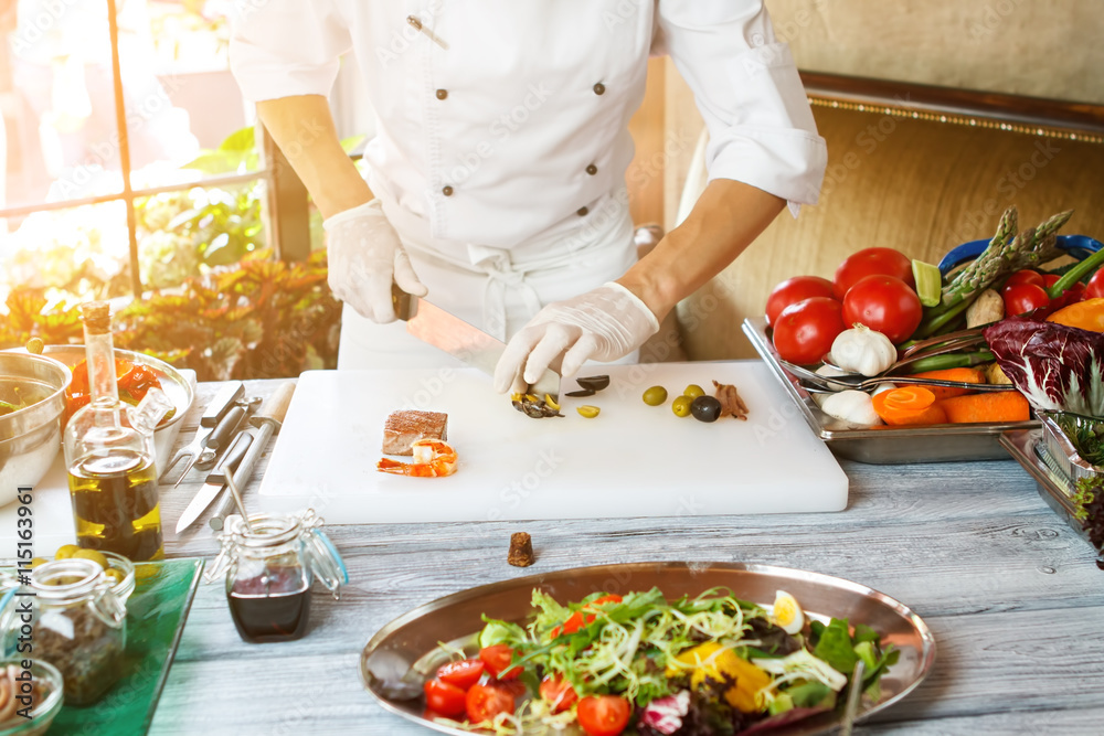 Hands with knife cut olives. Vegetable salad on tray. Green olives for tasty salad. Restaurant chef has serious skills. Hands with knife cut olives. Vegetable salad on tray. Green olives for tasty salad. Restaurant chef has serious skills.