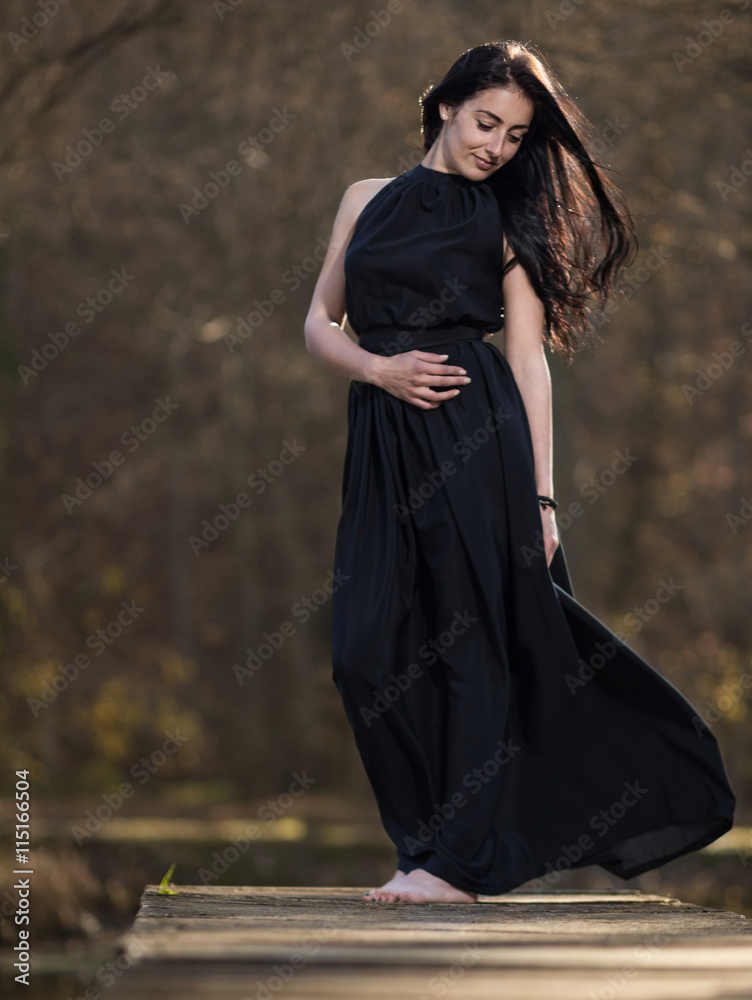 Naklejka premium Young woman in evening dress on the pier