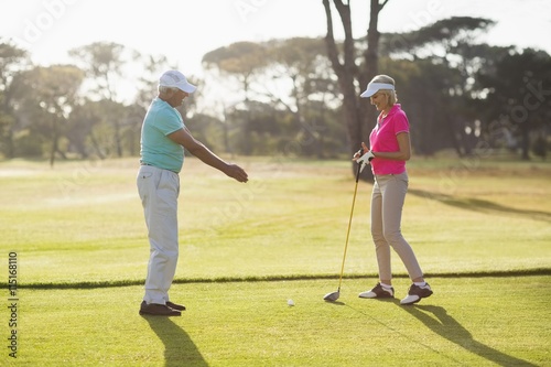 Side view of mature male golf player teaching woman