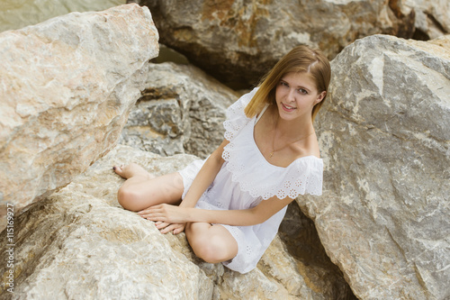 young slender girl is resting on the sea sitting on the rocks