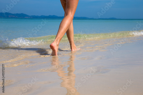 Woman walking on sand beach leaving footprints in the sand