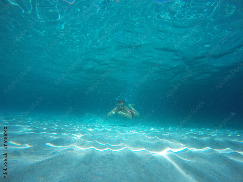 Beard man with glasses diving in a blue clean water