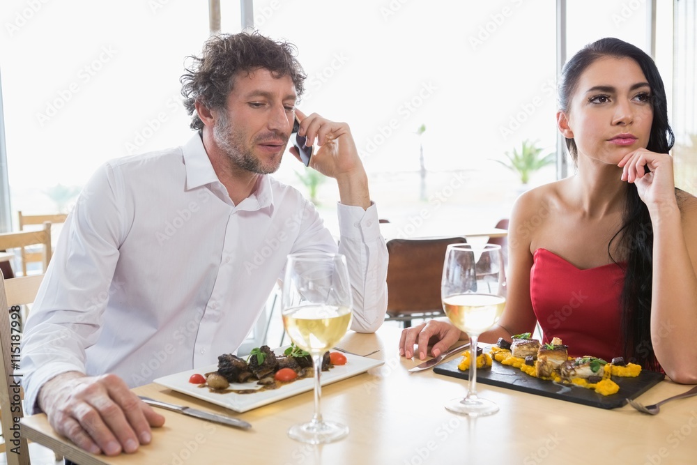 Woman sitting while man talking on mobile phone Woman sitting while man talking on mobile phone