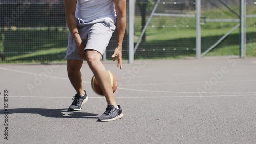 4K Unseen man dribbling a basketball with skill, in slow motion, with space for text photo