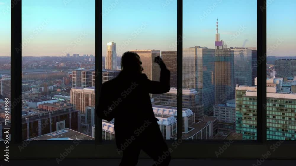 Happy business man celebrates in front of modern office window skyscrapers background Happy business man celebrates in front of modern office window skyscrapers background
