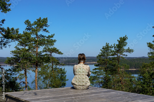 woman sitting and looking at the river from the top of the mountain
