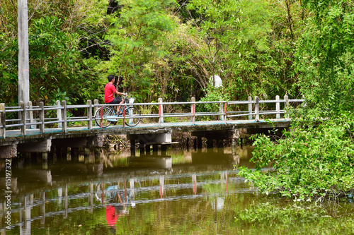 a man is biking on the bike path besides the canal at Bang Kachao Park