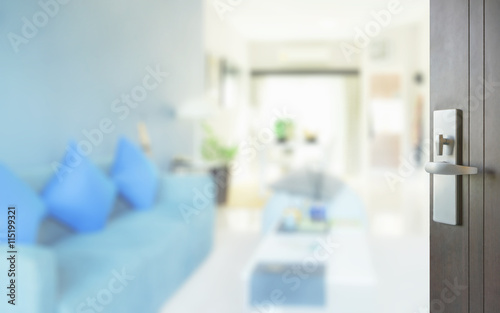 opened wooden door to modern living room interior with blue sofa set © worldwide_stock