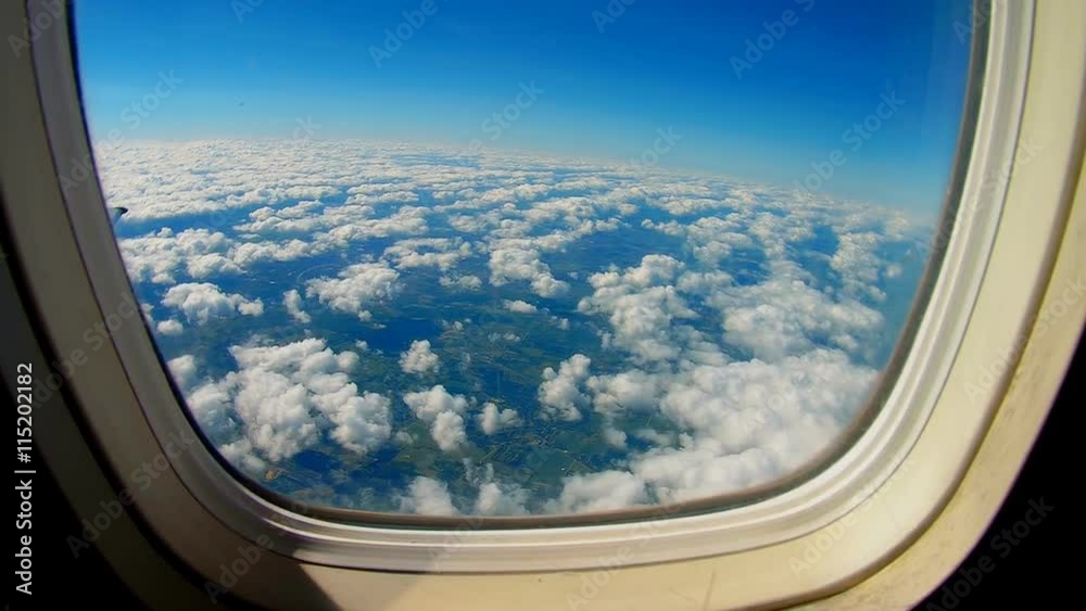 Airplane is flying in the blue sky through the white clouds. View of the airplane wing from the window. Airplane is flying in the blue sky through the white clouds. View of the airplane wing from the window.