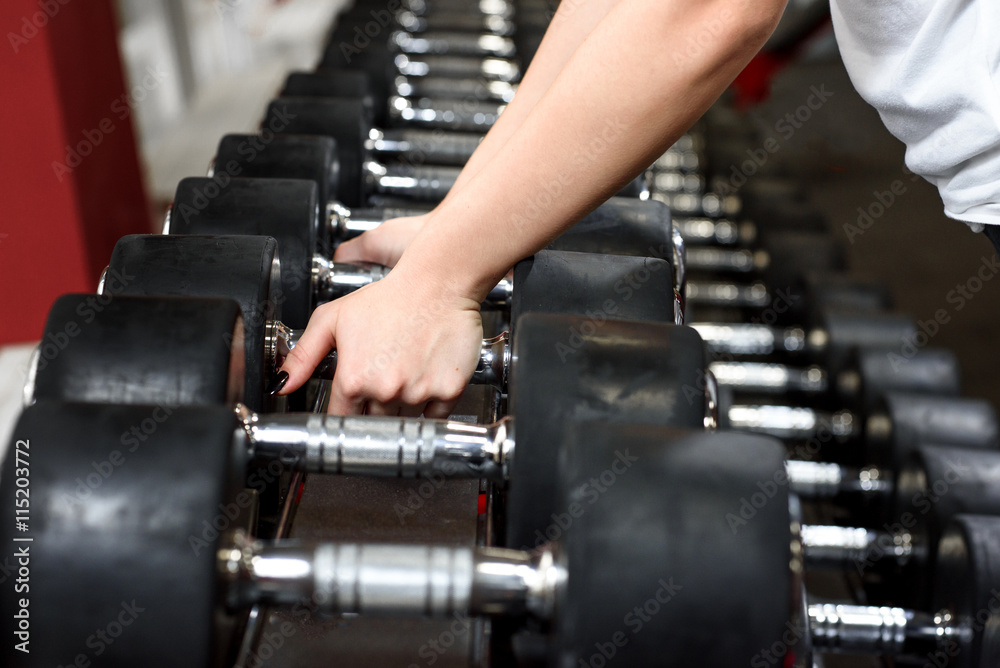 Close-up female hands choosing a dumbbell Close-up female hands choosing a dumbbell