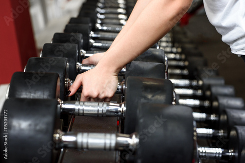 Close-up female hands choosing a dumbbell