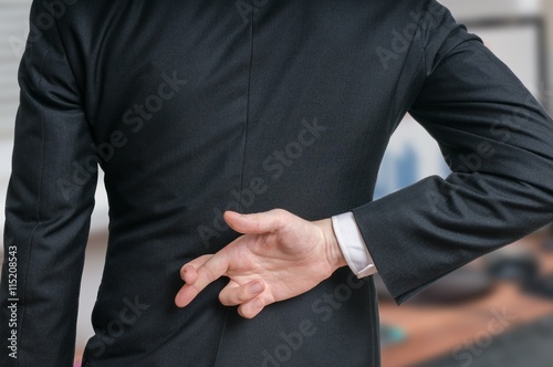 Businessman has crossed fingers behind his back. Good luck or dishonesty concept. photo