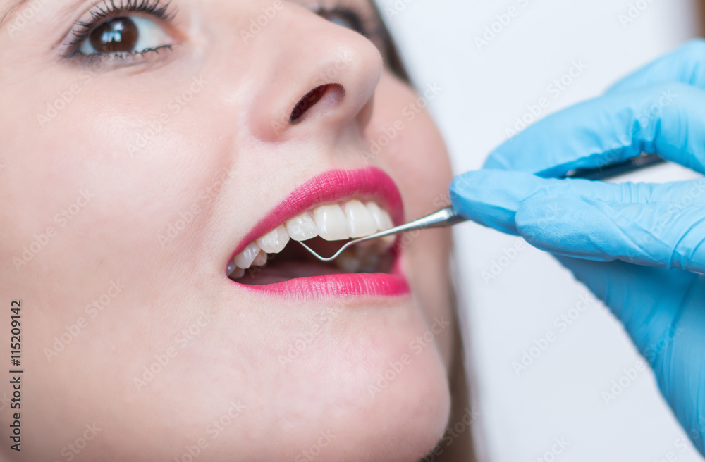 Close-up of young woman at dental visit. Stomatologist examining a young lady's teeth Close-up of young woman at dental visit. Stomatologist examining a young lady's teeth