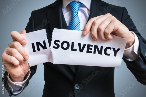 Debt relief concept. Businessman is tearing paper with insolvency to make solvency word. photo