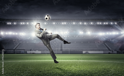 Businessman kicking ball . Mixed media