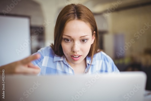 Surprised businesswoman working on laptop in office photo