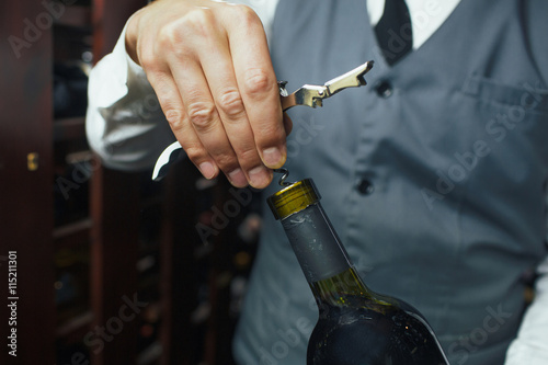 Sommelier opening wine bottle in the wine cellar