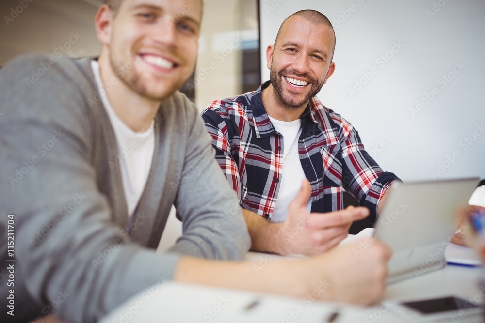 Happy businessmen using digital tablet at desk in office