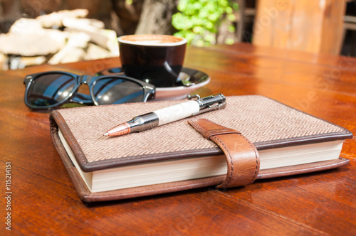 Close-up of pen agenda shades and coffee on terrace