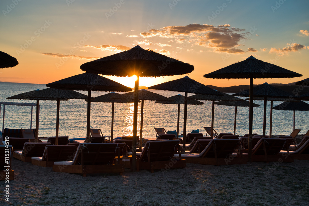 Straw parasols on a beach at sunset in Sithonia, Greece