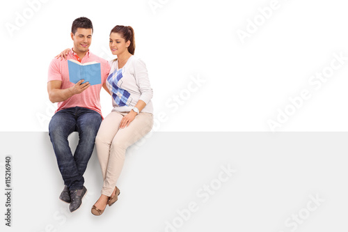 Couple reading book seated on a panel