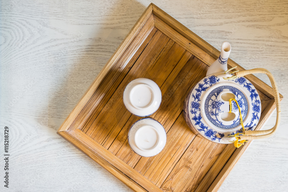 top of traditional white cup of tea and teapot in wooden tray cl