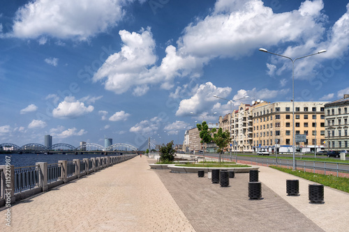 Quay of Daugava river with bridge and skyscraper in the city of