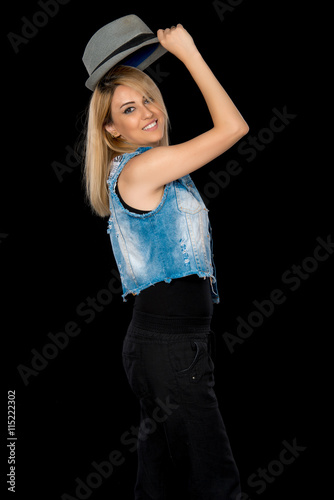 Portrait of beautiful model in black clothes, blue jeans and hat on black background