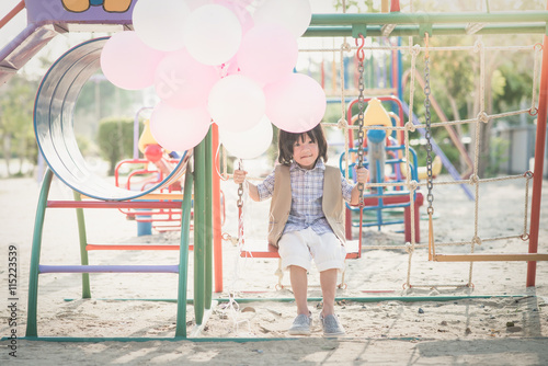 Asian child on a swing on summer day