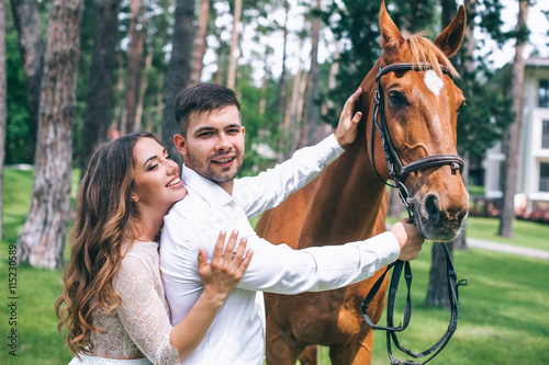A newlywed couple standing next to a horse