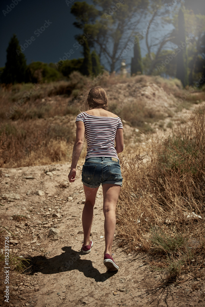Young Caucasian woman traveler climbing on mountain, having trip in Spain. Female hiker walking to the peak of the hill on rough trail. Young Caucasian woman traveler climbing on mountain, having trip in Spain. Female hiker walking to the peak of the hill on rough trail.