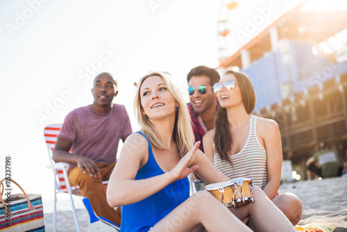 Young woman with friends bongo drumming on beach, Santa Monica, California, USA photo
